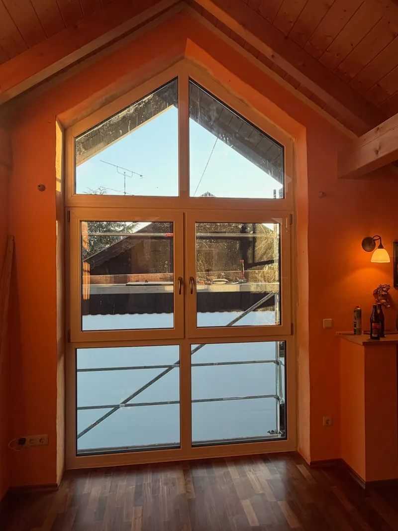 Neu eingebautes Giebelfenster aus Holz in einem Altbau-Dachgeschoss