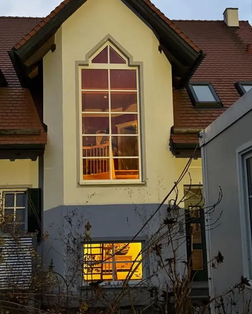 Beleuchtetes Sprossenfenster im Giebel eines Wohnhauses